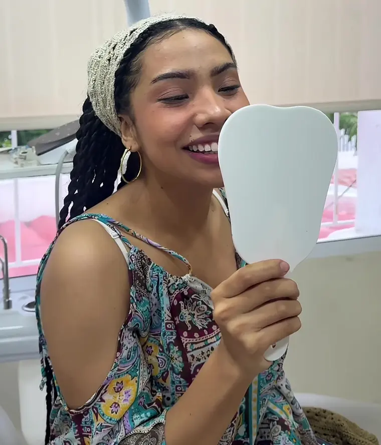 Paciente feliz viendo su nueva sonrisa en el espejo